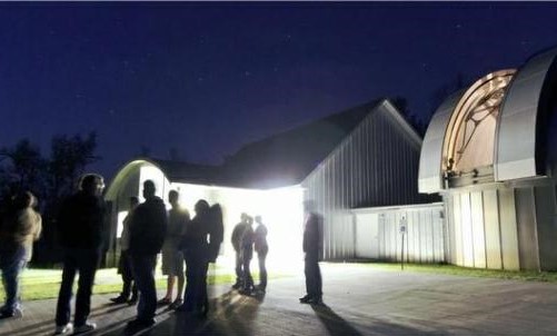 Group of people standing outside an observatory at night time