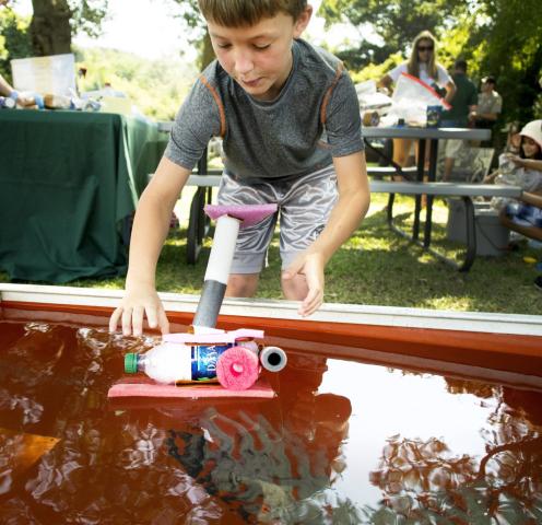 A kid creating a small boat from a water bottle and other materials