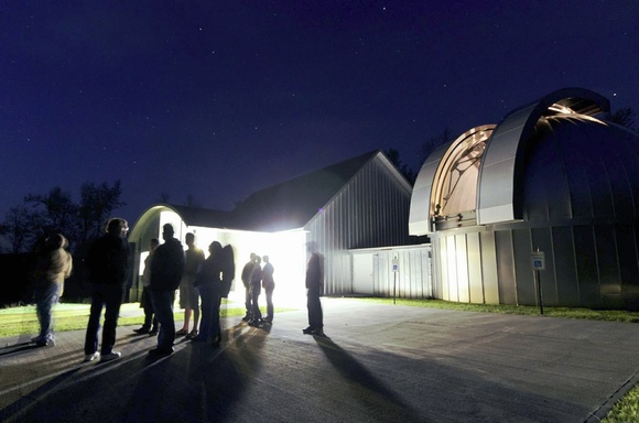 People outside of an observatory at night