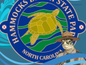 A logo of Hammocks Beach State Park. The logo has a golden sea turtle in the center of a blue circle with the park's name.  Blue waves wash across the logo and a loggerhead sea turtle dressed in a ranger's uniform is in the bottom right corner